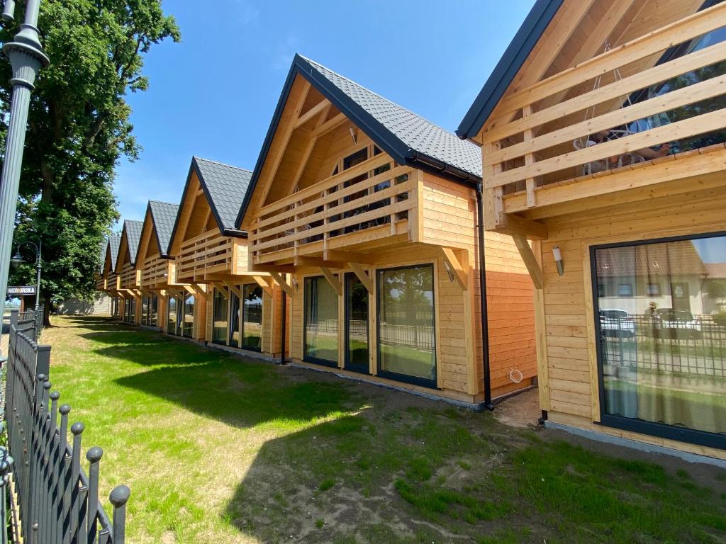 a row of wooden buildings with a fence at Ośrodek Wypoczynkowy Złote Piaski in Jarosławiec