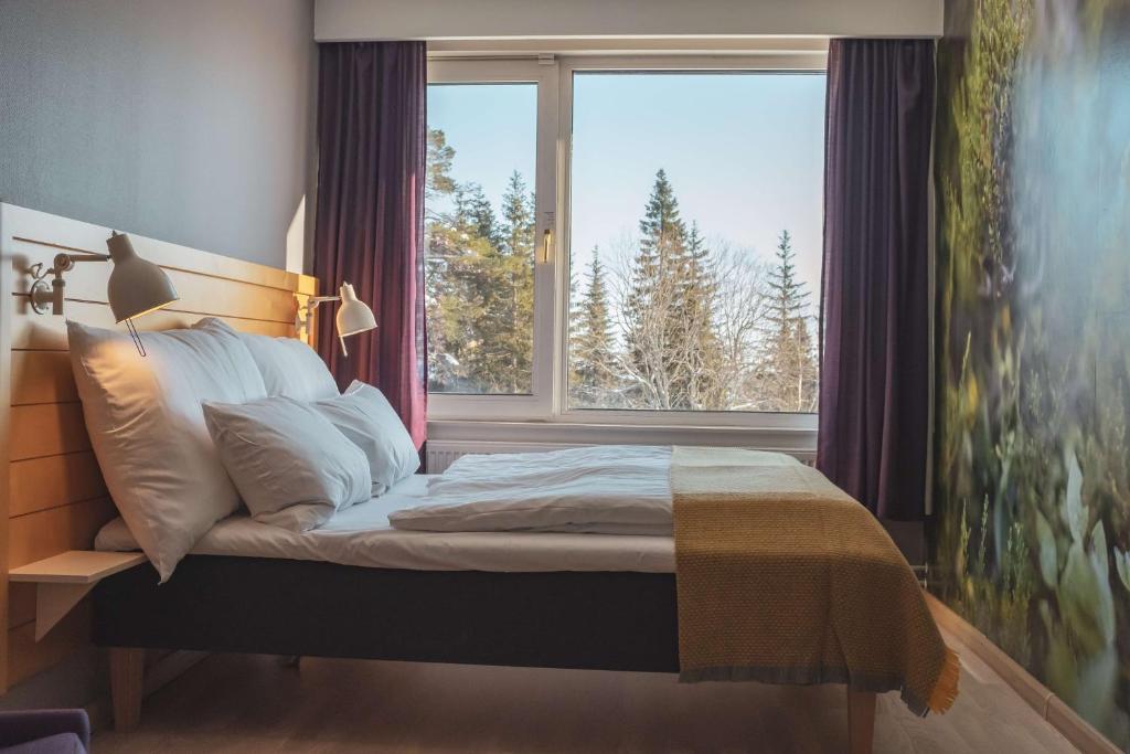 a bed in a bedroom with a large window at Voksenasen Hotell; Best Western Signature Collection in Oslo