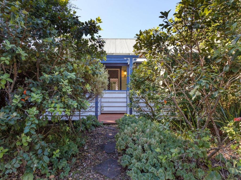 a small blue house through the trees at Witts Oasis Two traditional Tea Gardens cottages in Tea Gardens