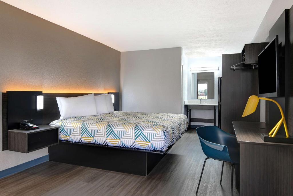 a hotel room with a bed and a desk at Studio 6 Meridian, MS Bonita Lakes in Meridian