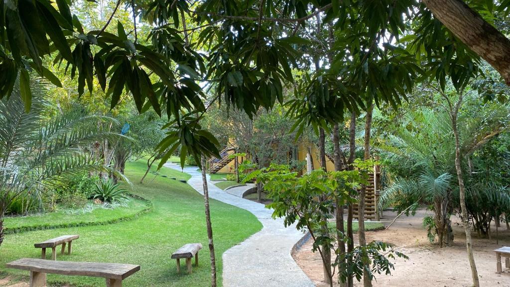 einen Park mit Bänken und einen Weg mit Bäumen in der Unterkunft Loft Reserva Sapiranga Praia do Forte Vila Hen 102 in Mata de Sao Joao