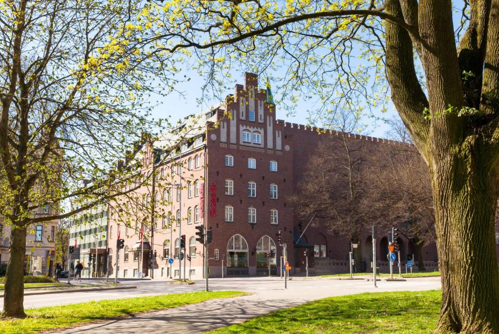 een groot gebouw van rode baksteen met een klokkentoren bij Scandic Frimurarehotellet in Linköping