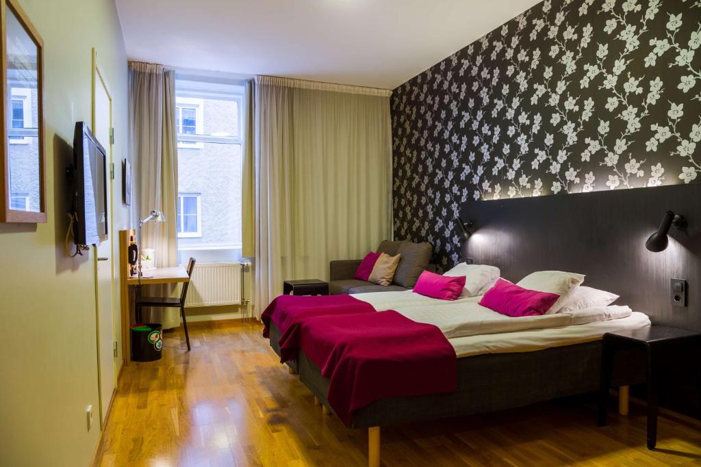 um quarto com uma cama grande e almofadas cor-de-rosa em Scandic Billingen em Skövde
