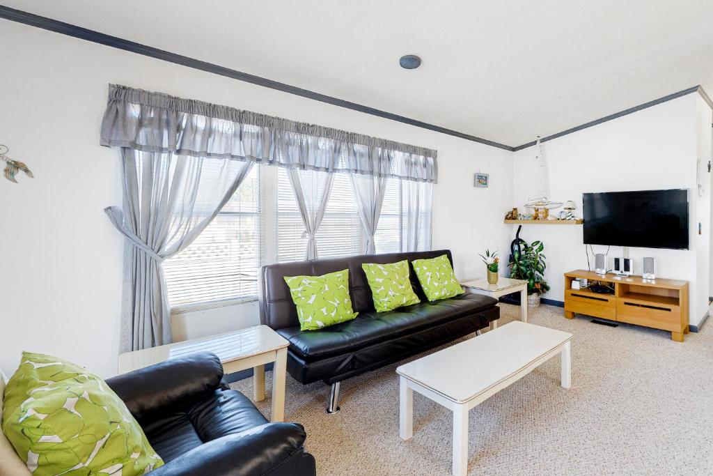 a living room with a black leather couch and a tv at Assateague Point - Bay Breeze in Berlin