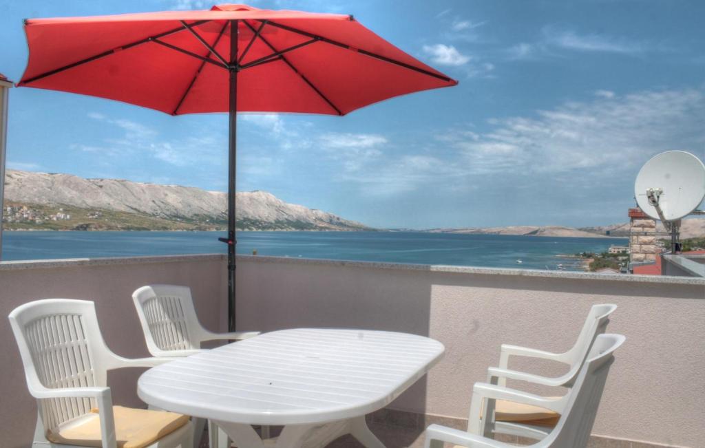 Petros Apartments Pag في باغ: طاولة وكراسي على شرفة مع مظلة حمراء