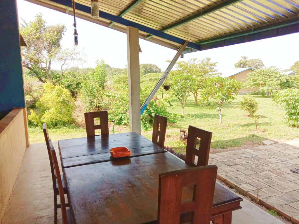 a wooden table and chairs in a porch with a yard at RHO Sigiriya Lake Edge Retreat & Spa in Sigiriya