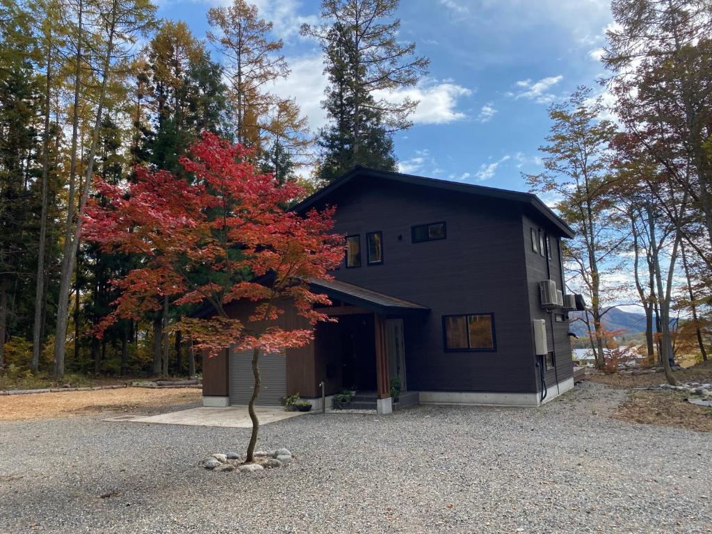 a house with a red tree in front of it at Hakuba Kaede House in Hakuba