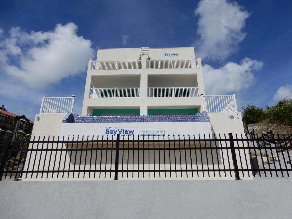a white building with a fence in front of it at Oistins Bayview Apartments in Christ Church