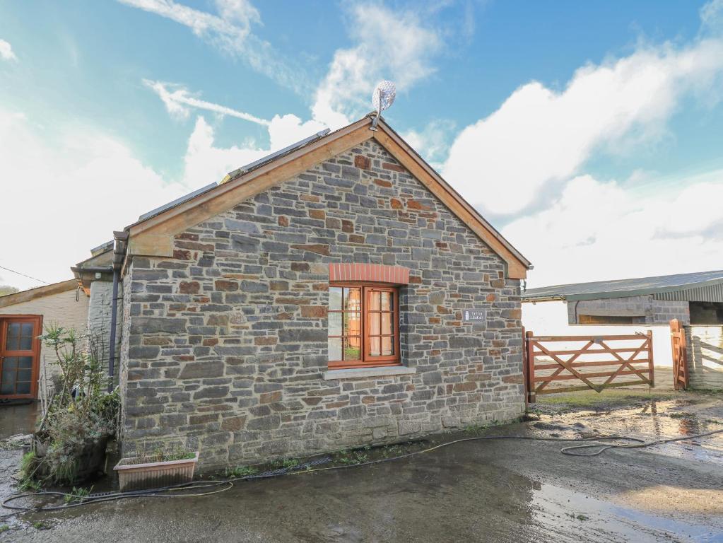 a small brick house with a window and a fence at Yr Hen Llaethdy in Troedyraur