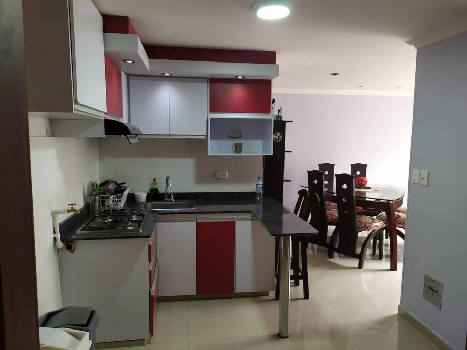 una cocina con armarios rojos y blancos y una mesa en Hermoso apartamento en Pasto. Central parque San Andrés, en Pasto