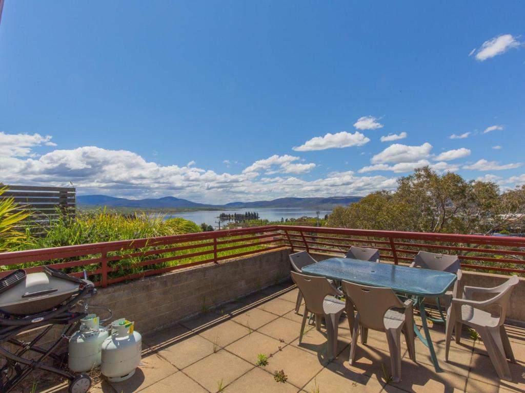 a table and chairs on a balcony with a view of the water at Tanderra 17 28 Park Road in Jindabyne