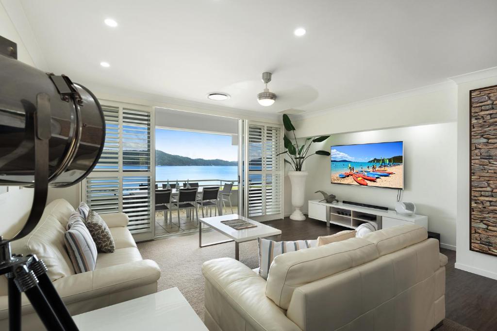 un soggiorno con un divano e una TV di Frangipani Beachfront Lodge 202 on Hamilton Island by HamoRent a Hamilton Island