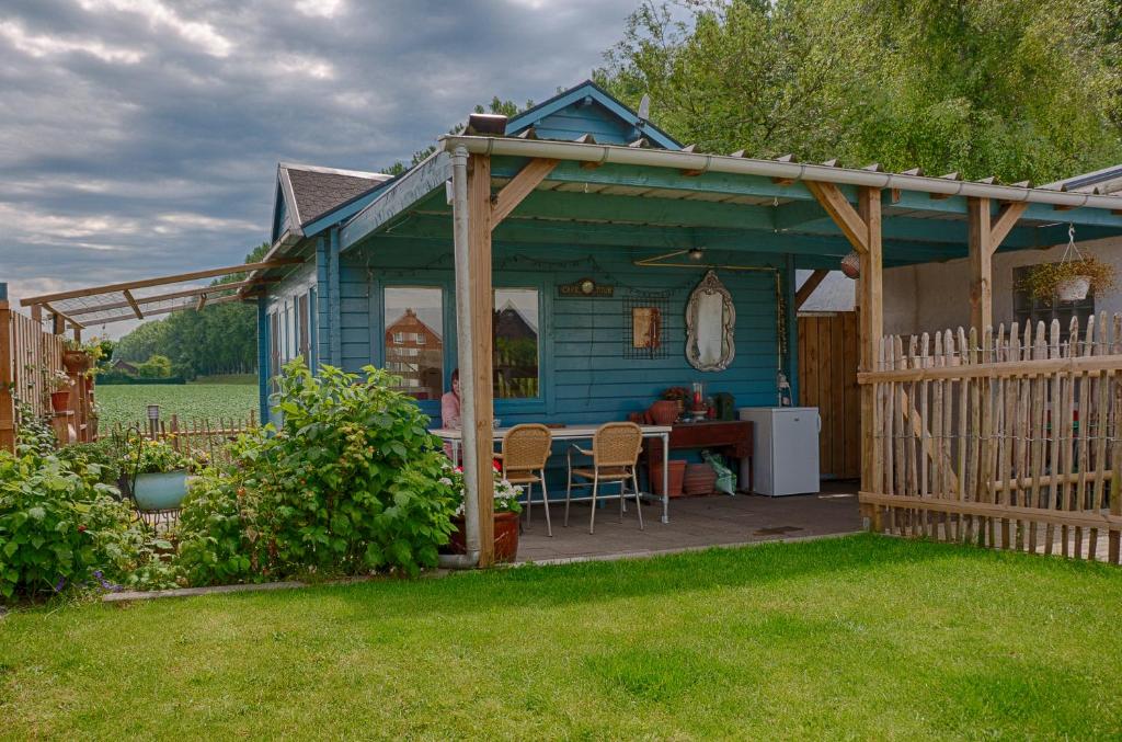 a blue house with a table in a yard at Artistiek Vakantiehuisje in Hulst