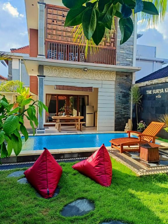 a house with a swimming pool and red pillows in the grass at The Surya Kuta Villa in Kuta