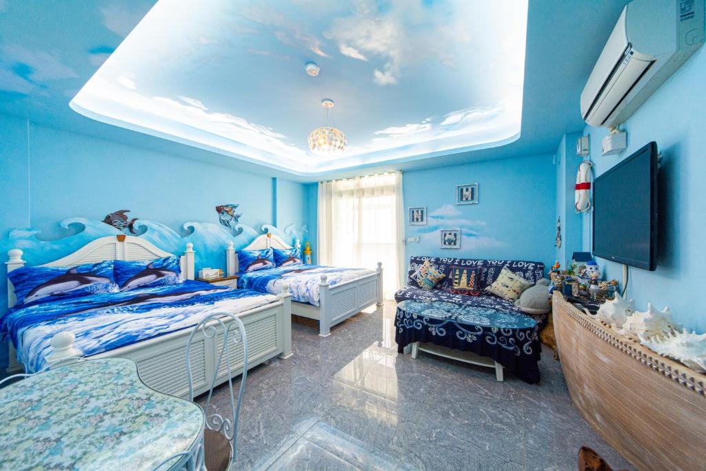 a blue room with two beds and a tv at Sunflower B&amp;B II in Hualien City