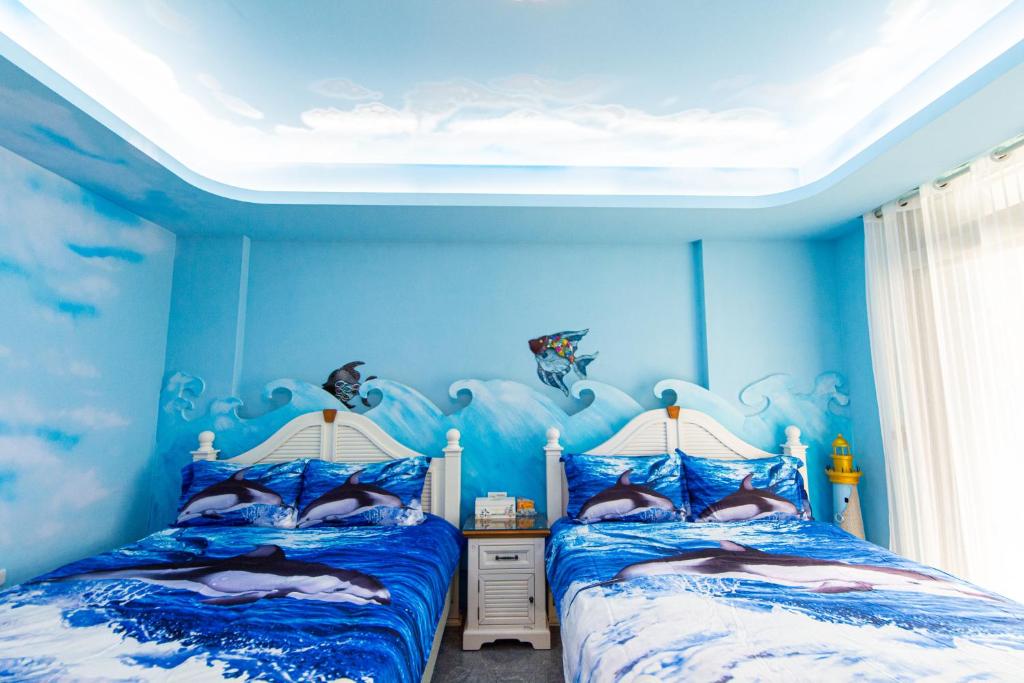 two beds in a room with blue walls at Sunflower B&amp;B II in Hualien City
