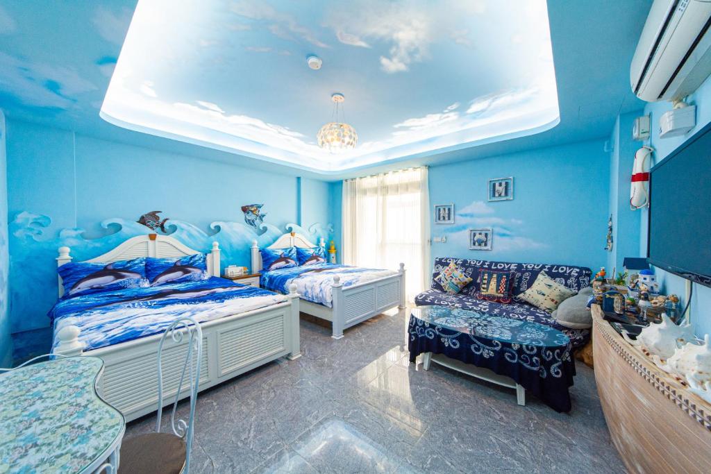 a blue room with two beds and a couch at Sunflower B&amp;B II in Hualien City