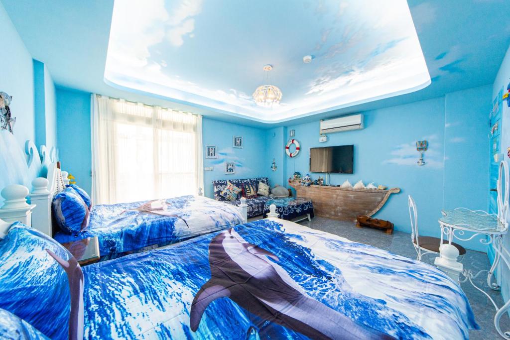 a blue room with two beds and a television at Sunflower B&amp;B II in Hualien City