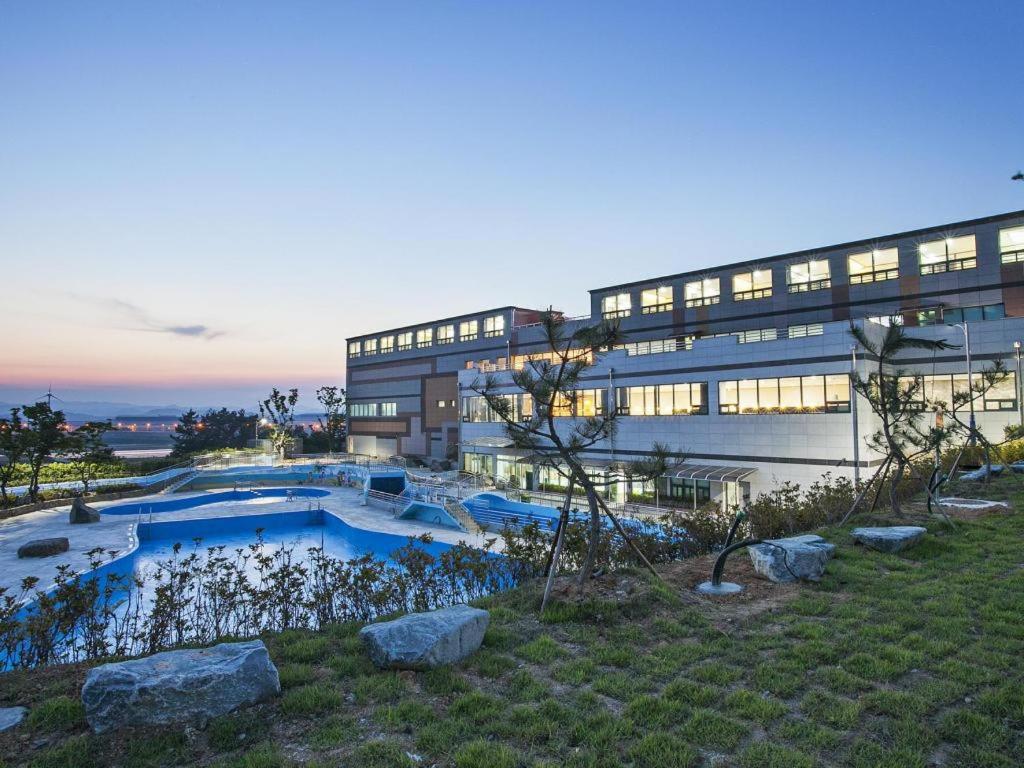 a building with a swimming pool in front of a building at Sacheon Grand Tourist Hotel in Sacheon