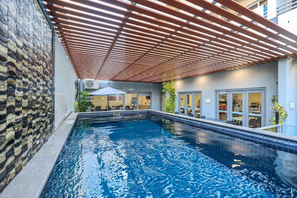an indoor swimming pool with a wooden ceiling at Argus Hotel Darwin in Darwin