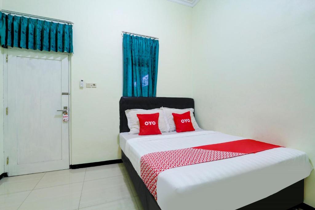 a bedroom with a bed with two red pillows at Capital O 90709 Djati Guest House in Kudus