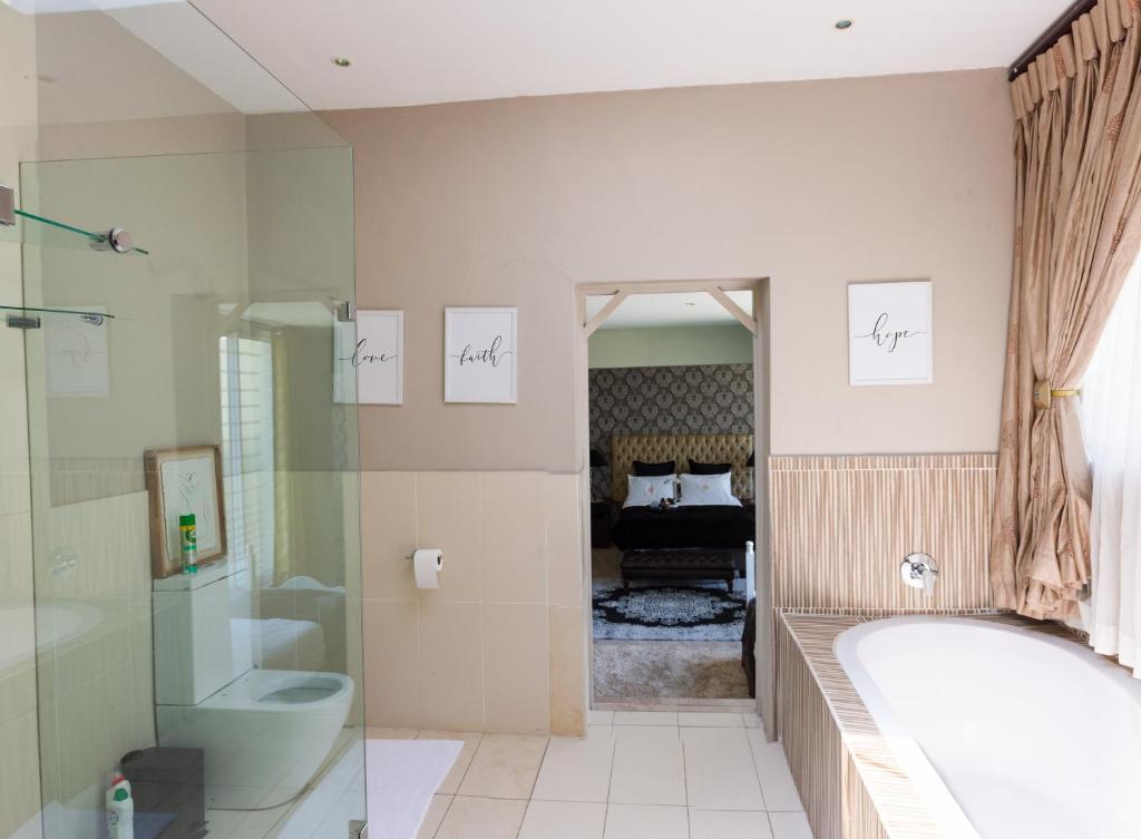 a bathroom with a tub and a toilet and a bed at The Houghton Villa in Johannesburg