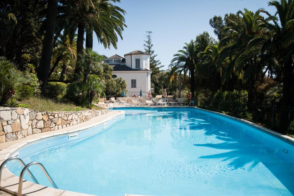 duży basen z domem w tle w obiekcie Residence RTA Villa Marina w mieście Imperia