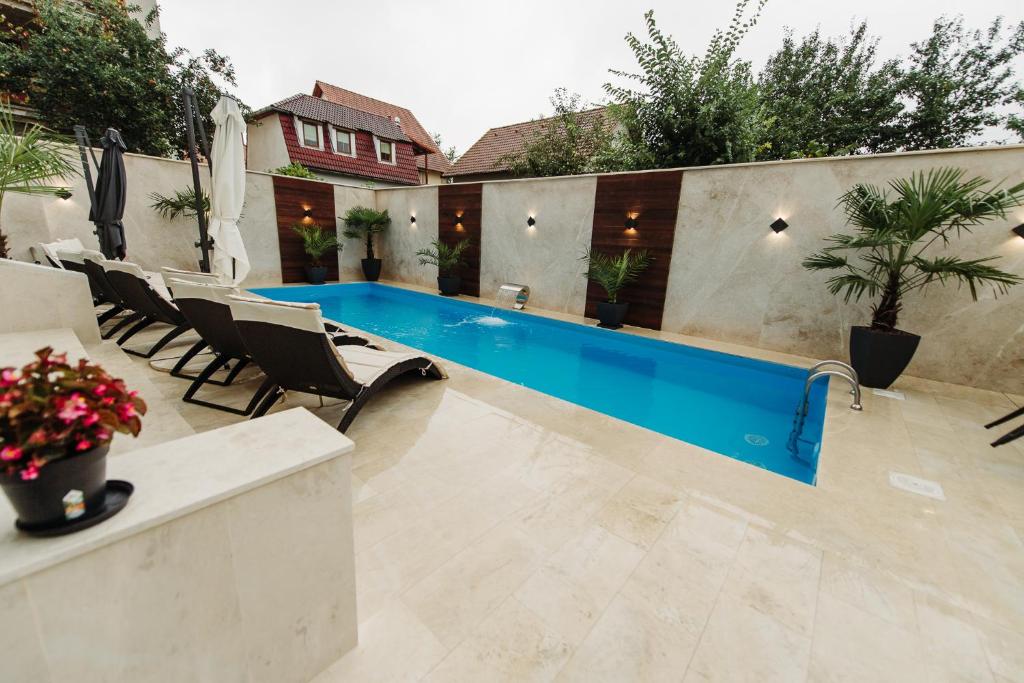 a swimming pool in a backyard with chairs and a table at Boutique Damiani in Sibiu