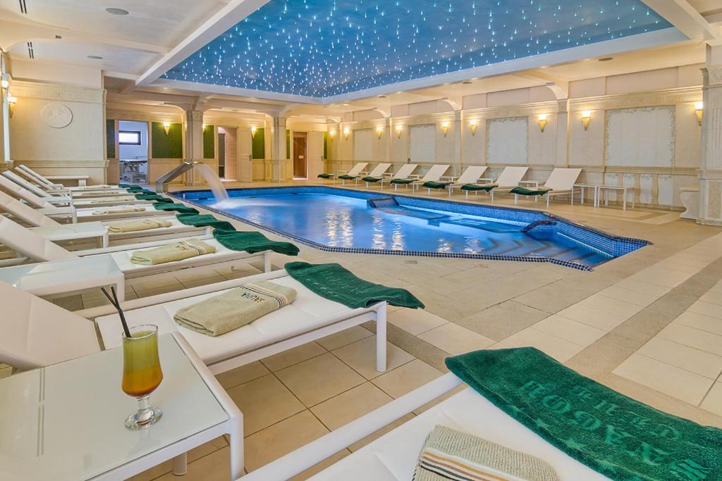 a hotel room with a pool, chairs, and tables at Hotel Snagov Club in Snagov