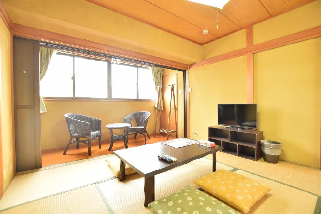 uma sala de estar com uma mesa e uma televisão em Matoba 6F in Dotonbori em Osaka