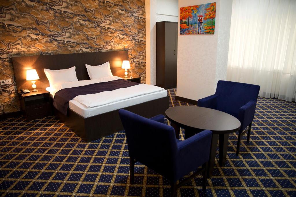 a hotel room with a bed and a table and chairs at Kristal Inn Hotel in Baku