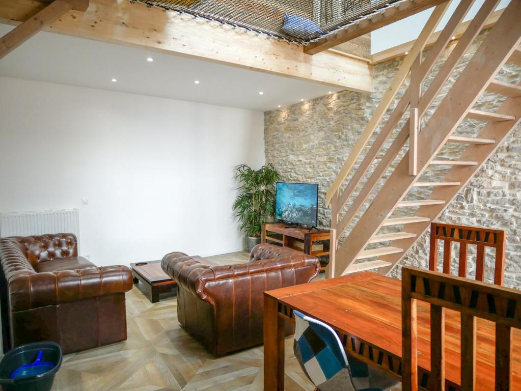 una sala de estar con muebles de cuero y una escalera. en Gîte des Augustins - gitesdesbalcons-com, en Crémieu
