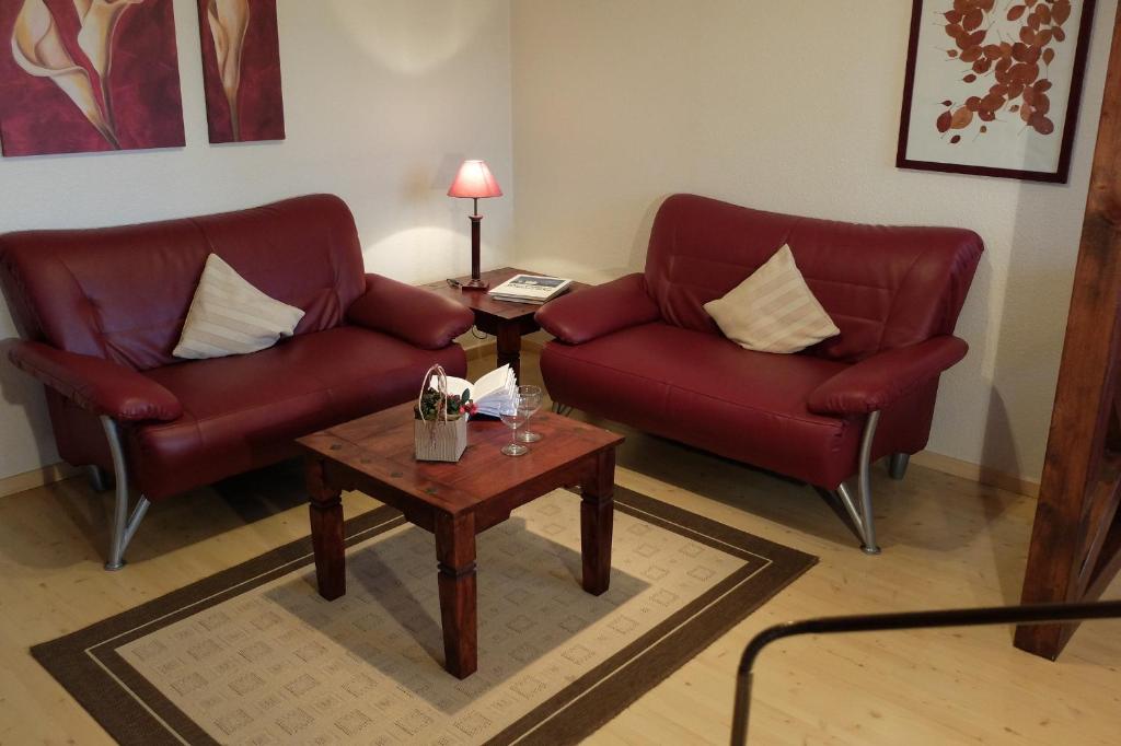 PommerbyにあるFerienwohnung Gartenblickのリビングルーム(赤い椅子2脚、コーヒーテーブル付)