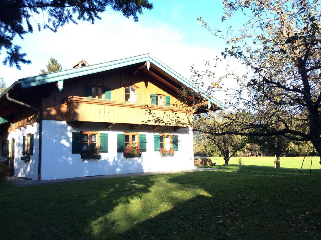Casa blanca con persianas verdes y patio en Ferienhaus Lois & Lisl, en Schleching