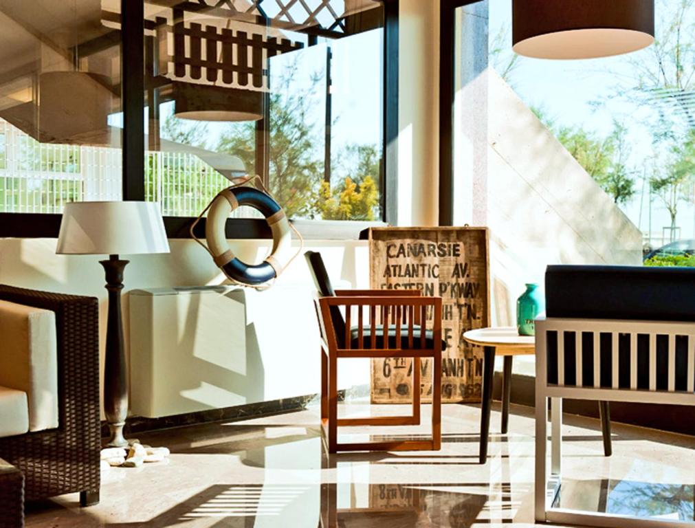 ペーザロにあるホテル アンバサダーの椅子とテーブル、窓が備わる客室です。
