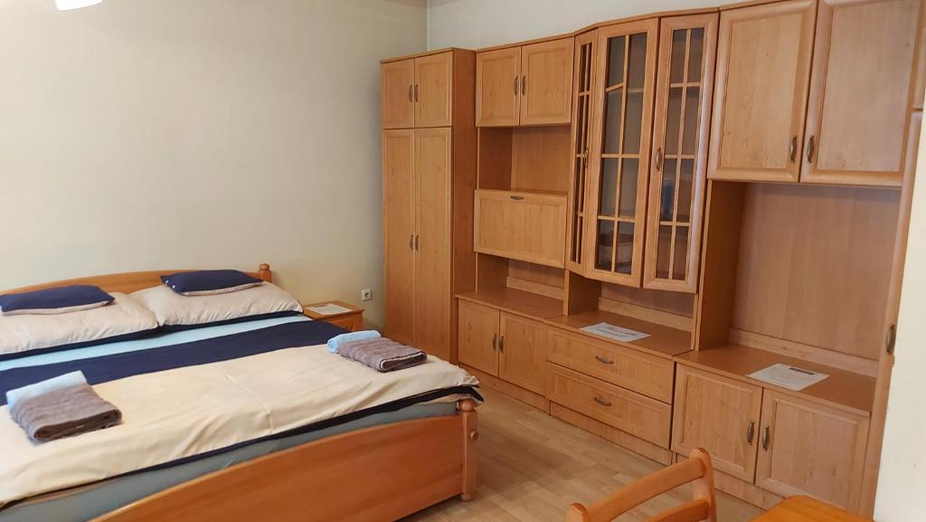 デブレツェンにあるPeró Apartmanのベッドルーム(ベッド2台、木製キャビネット付)