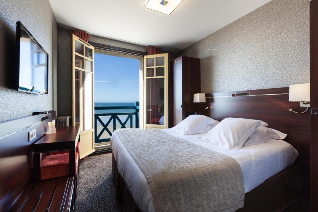 um quarto com uma cama e vista para o oceano em Ambassadeurs Logis Hotel em Saint Malo