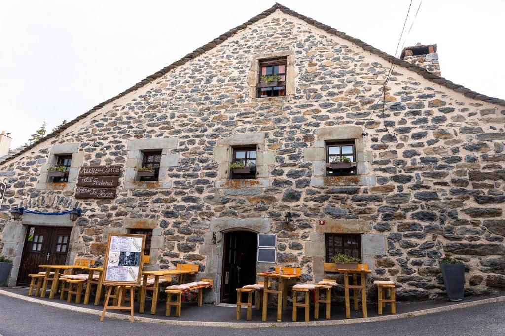 a stone building with tables and chairs in front of it at Auberge des Calades in Les Estables