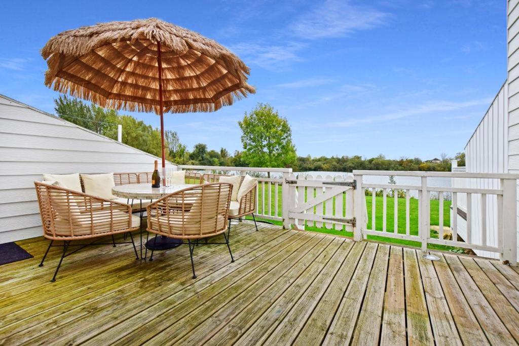 a wooden deck with a table and an umbrella at Luxury lodge in the heart of the Cotswolds in Cirencester