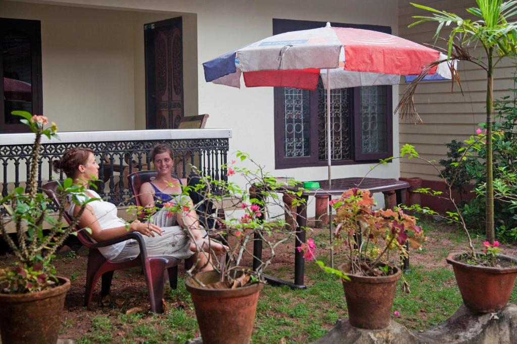 Due donne sedute in veranda con un ombrello di Dream Nest Guest House a Alleppey