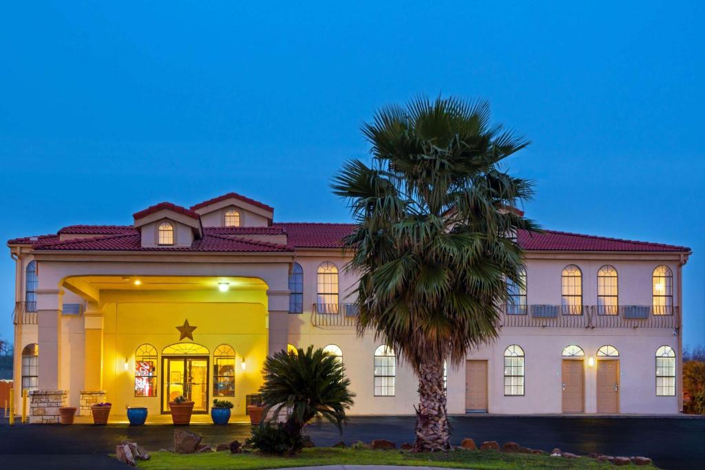 a large house with a palm tree in front of it at Days Inn by Wyndham Seaworld Lackland AFB in San Antonio