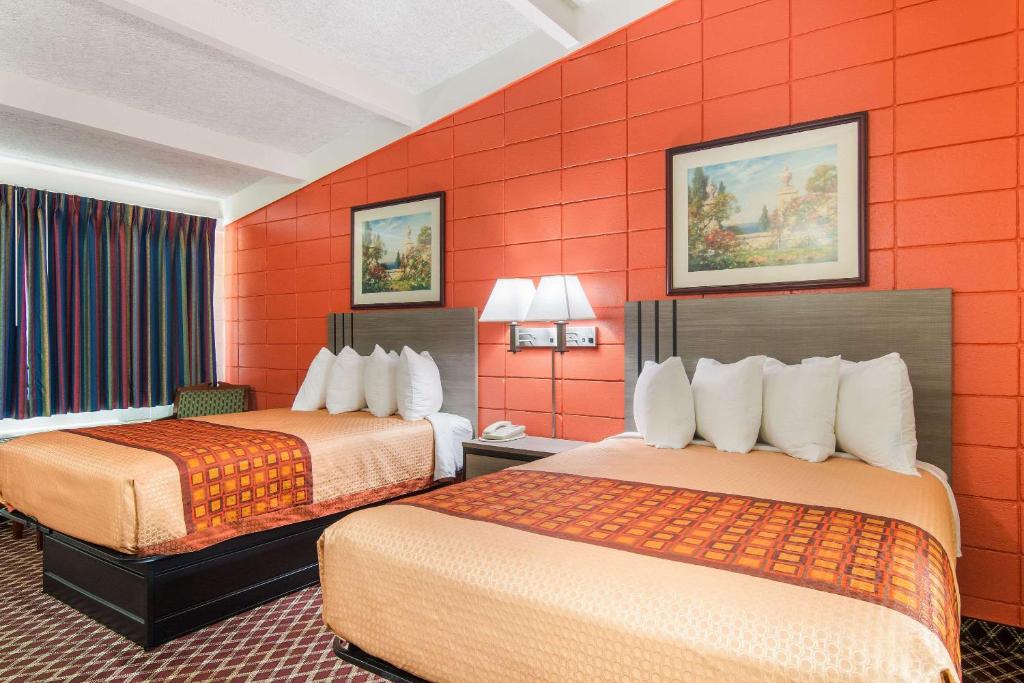 two beds in a hotel room with orange walls at Rodeway Inn in Nashville