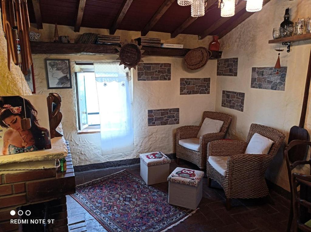 een woonkamer met 2 stoelen en een raam bij Accogliente casa in pietra in borgo medievale in Serra Pistoiese