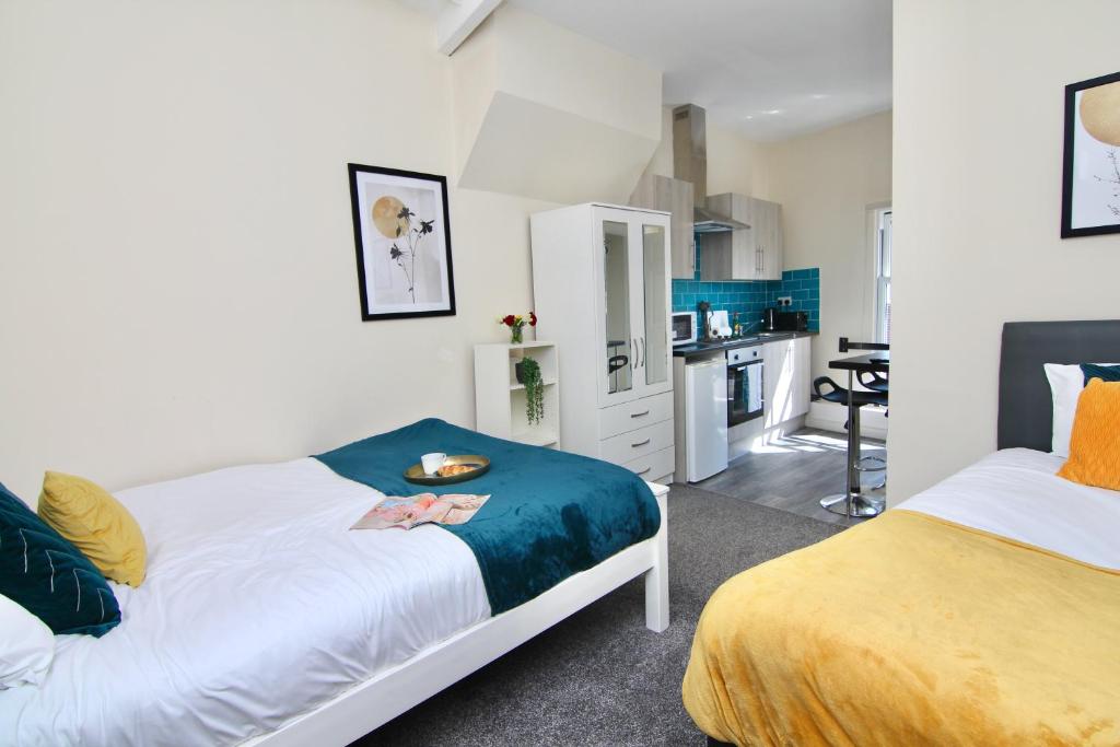 a bedroom with two beds and a kitchen at Cute Studio 4 mins Walk To Planet Ice, Sleeps 3 in Coventry