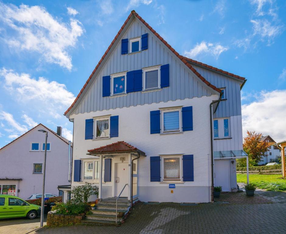 een wit huis met blauwe luiken bij Ferienwohnung Schuhmacherwerkstatt Wilhelm Wendel in Loßburg