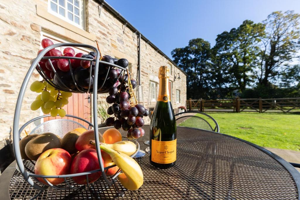 a table with a basket of fruit and a bottle of wine at The Byre in Stanhope