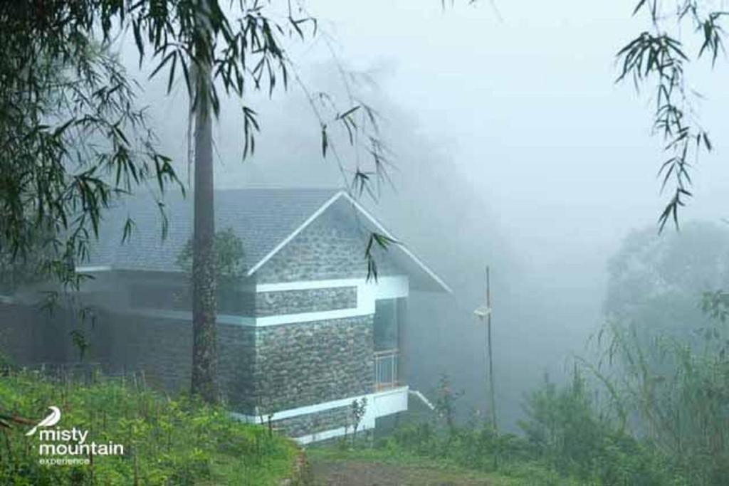 Ein Haus im Nebel mit einem Gebäude in der Unterkunft Misty Mountain Experience in Pīrmed