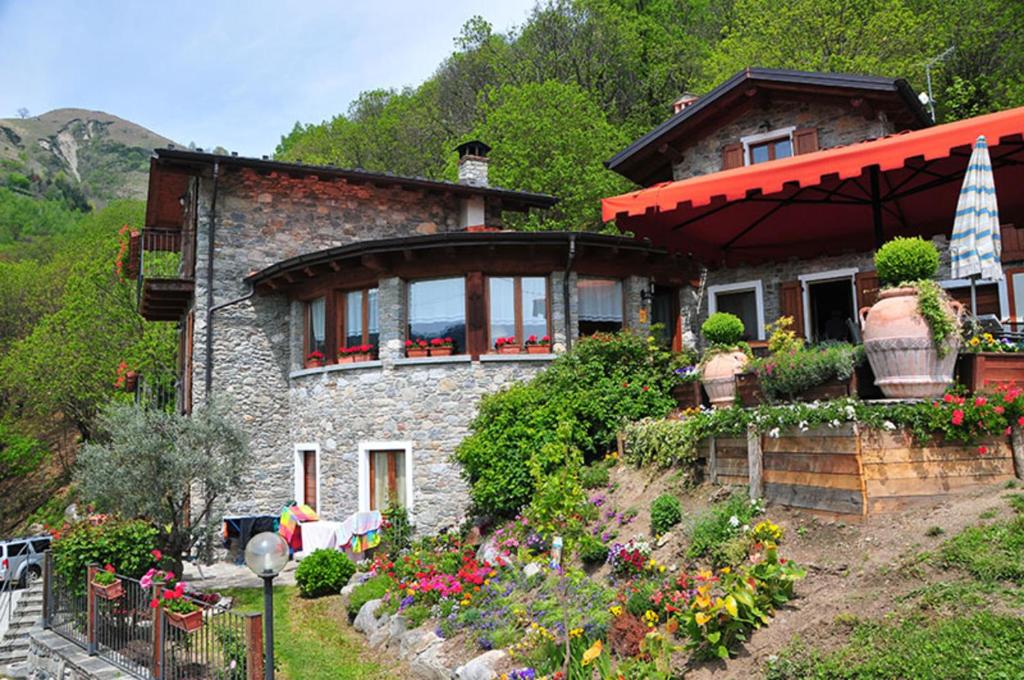 una casa de piedra con flores delante en La Fonte di Mariella Monolocale 2 en Dosso del Liro