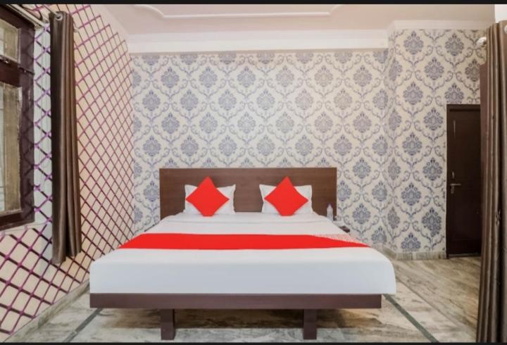 ein Schlafzimmer mit einem Bett mit roten Kissen darauf in der Unterkunft Welcome Guest Accommodation in Kalkutta