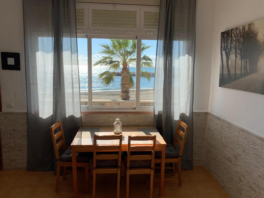 ein Esszimmer mit einem Tisch, Stühlen und einem Fenster in der Unterkunft Apartamento frente al Mar - Pedregalejo in Málaga